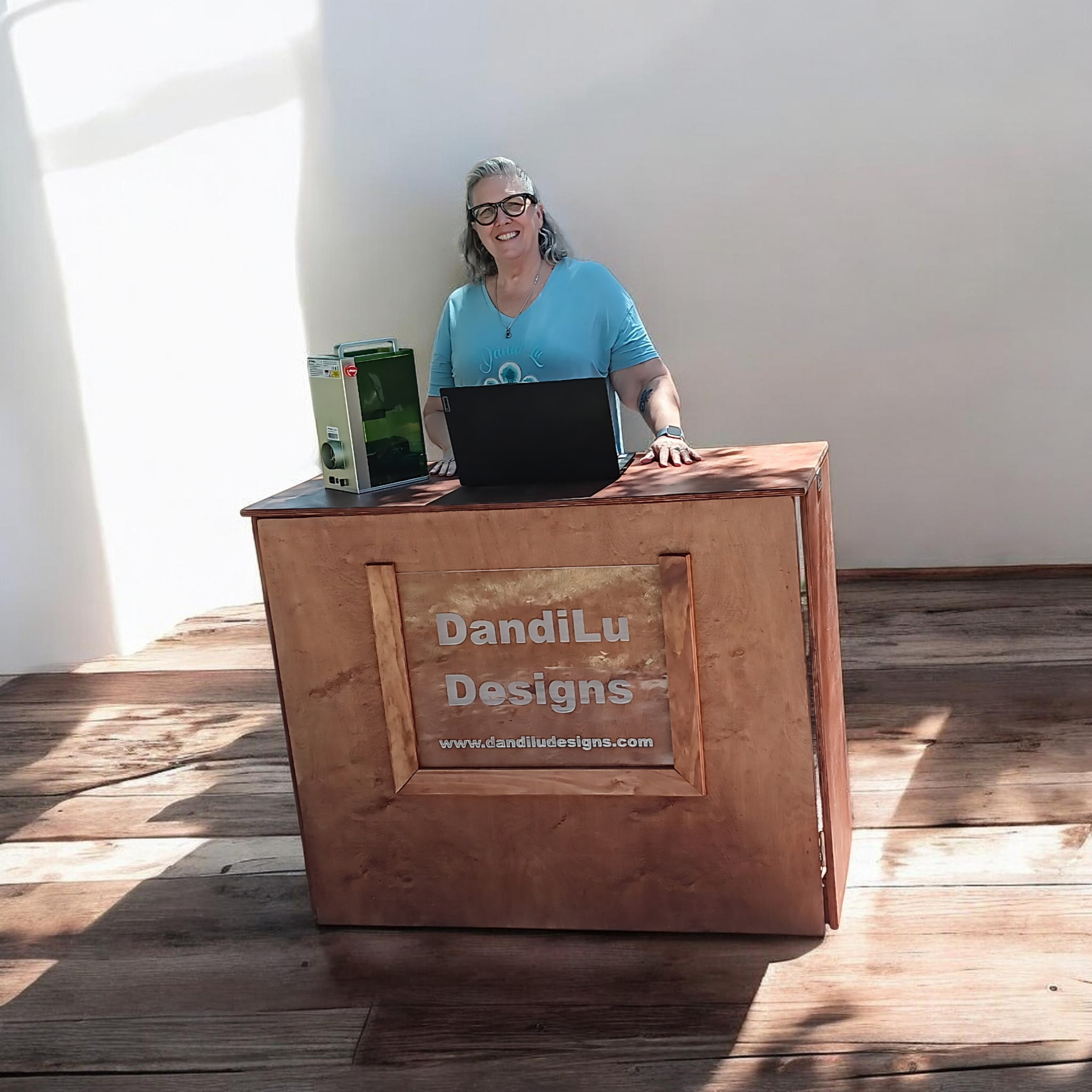 Randi at the DandiLu Designs engraving station with laser engraver and laptop