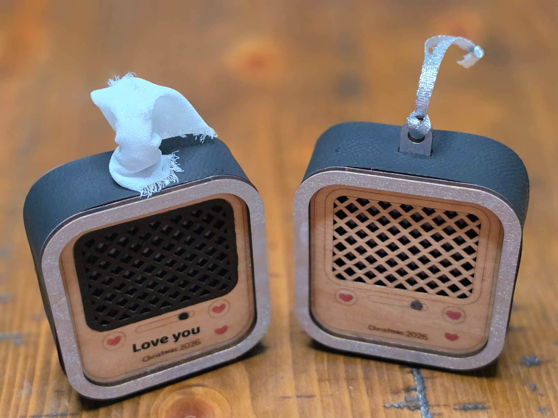 Two retro radio voice ornaments engraved with a personal message and the year, standing on a wooden table