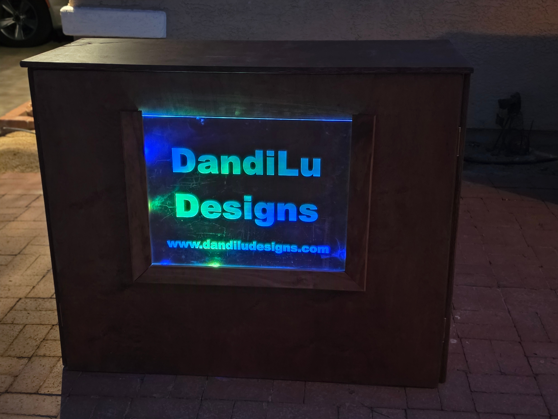 DandiLu Designs engraving station illuminated with LED-lit acrylic sign at night