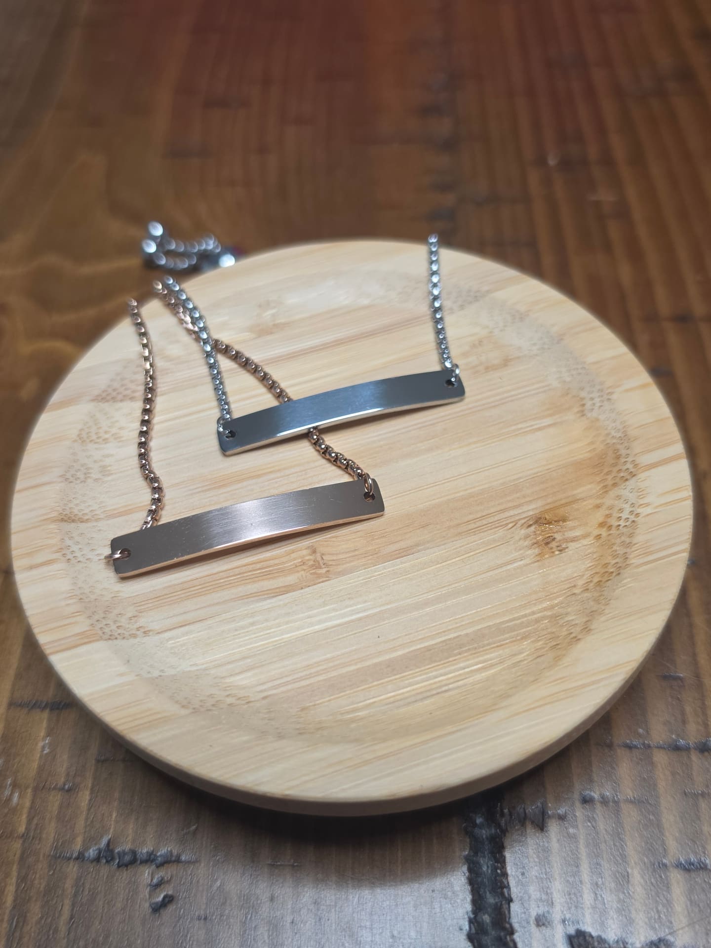 Silver and rose gold engravable bar necklaces on bamboo dish